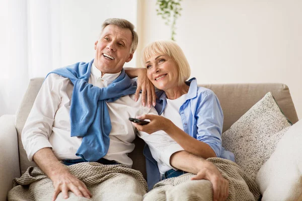 Расслабленная зрелая пара отдыхает и смотрит телевизор дома — стоковое фото