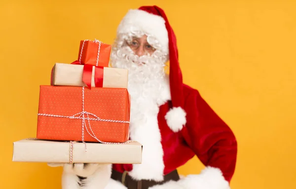 Weihnachtsgeschenke in buntem Papier Weihnachtsmann hält auf orange gewickelt — Stockfoto