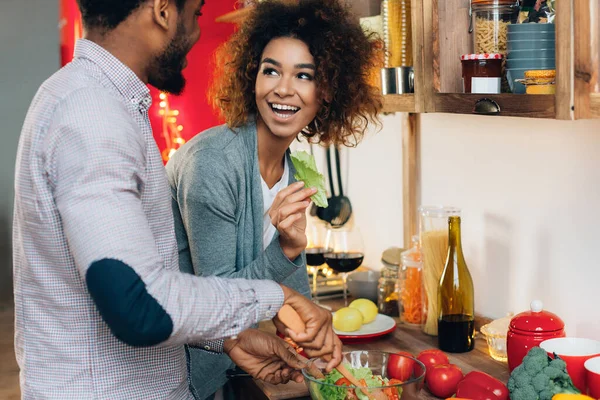 Young african-american couple preparing salad in kitchen — Stock Photo, Image
