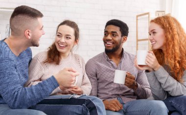 Neşeli arkadaşlar çay içip evde konuşuyorlar.