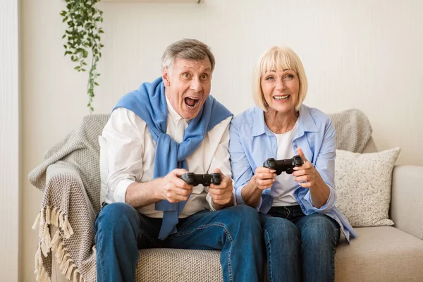 Pareja madura muy alegre jugando videojuegos en casa — Foto de Stock