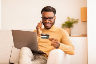 İnternette telefonla konuşan adam kanepede oturuyor.