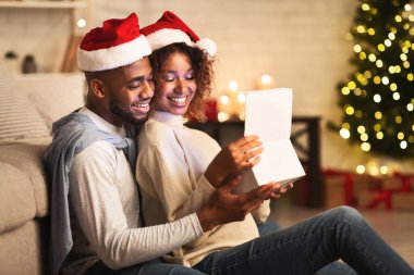 Tatlı çift Noel hediyesini açıyor, Noel Baba şapkası takıyorlar.