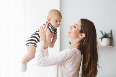 Milenyum annesi yeni doğmuş bebeğiyle evde oynuyor.