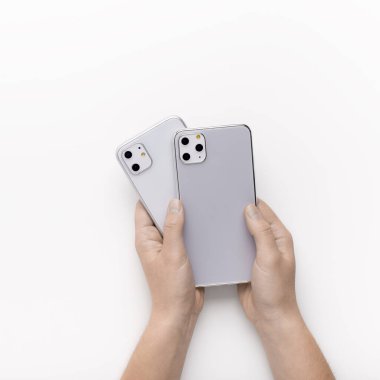 Müşteri elinde farklı kameralı iki yeni iPhone tutuyor.