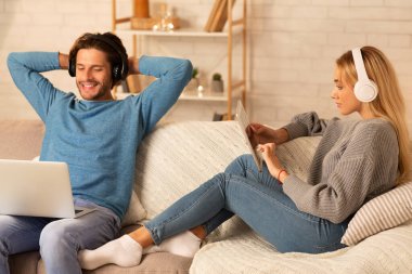 Rahat çift laptop ve tablet kullanıyor. Kapalı koltukta oturuyor.