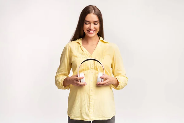 Smiling Pregnant Lady Standing Holding Headphones Near Belly, White Background — Stock Photo, Image