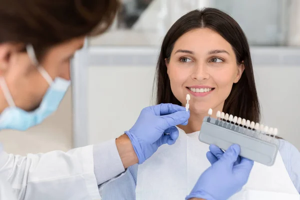 Zahnarzt appliziert Probe von der Zahnwaage auf lächelnde Patientenzähne — Stockfoto