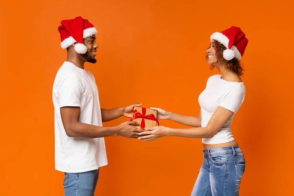 Couple millénaire noir avec cadeau de Noël sur fond orange — Photo