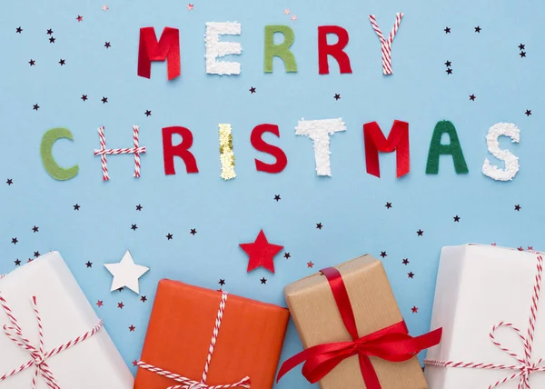 Feliz Navidad deseos y regalos en cajas sobre fondo azul — Foto de Stock