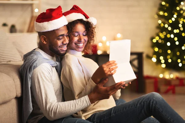 Doce casal abrindo presente de Natal, vestindo chapéus de Papai Noel — Fotografia de Stock