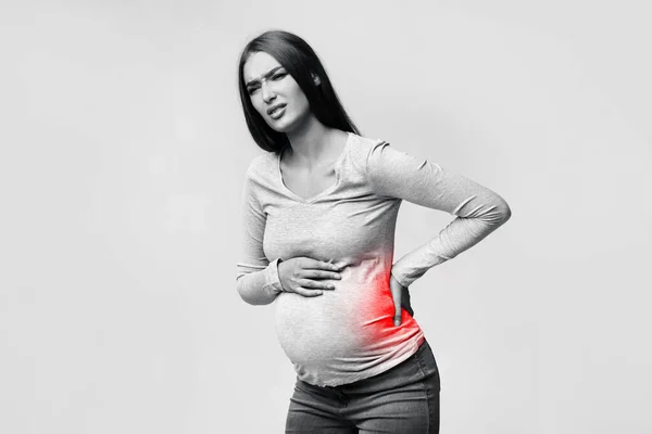 Femme enceinte ayant mal au dos debout dans le studio — Photo
