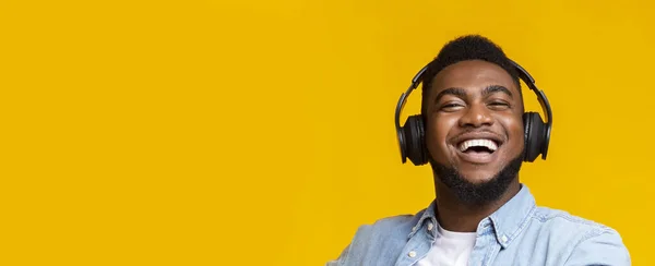 Hombre afroamericano en audífonos modernos sonriendo sobre fondo amarillo — Foto de Stock