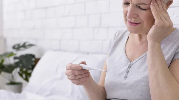 Señora mayor con dolor de cabeza que sufre de fiebre, la medición de la temperatura corporal —  Fotos de Stock