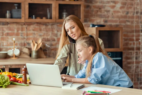 Девушка прерывает свою работающую маму, используя ноутбук — стоковое фото
