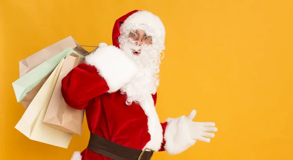 Santa Claus va por regalos con bolsas de papel ecológico en naranja — Foto de Stock