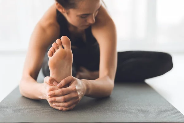 Fit woman warmup stretching, training indoors, focus on foot — Stock Photo, Image