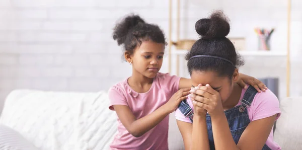 En liten afrikansk amerikansk flicka som tröstar sin gråtande äldre syster. — Stockfoto