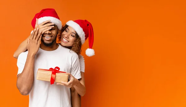 Couple millénaire noir avec cadeau de Noël sur fond orange — Photo