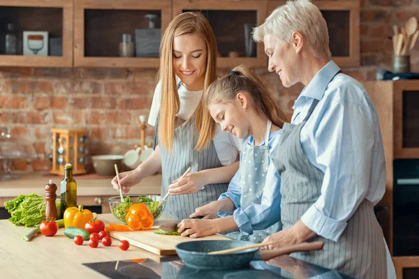 Glückliche erwachsene Damen, die kleinen Mädchen das Kochen beibringen — Stockfoto