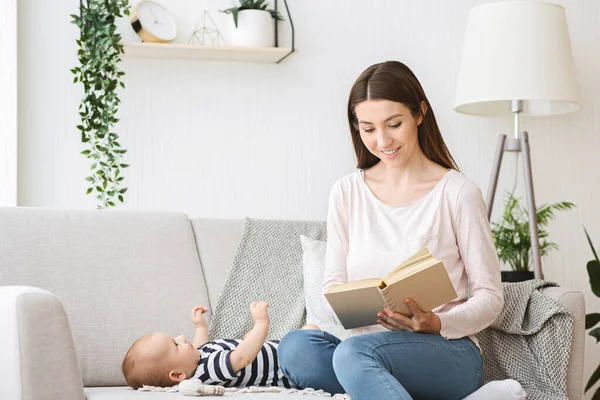 Zorgzame Moeder voorlezen boek naar haar pasgeboren kind. — Stockfoto