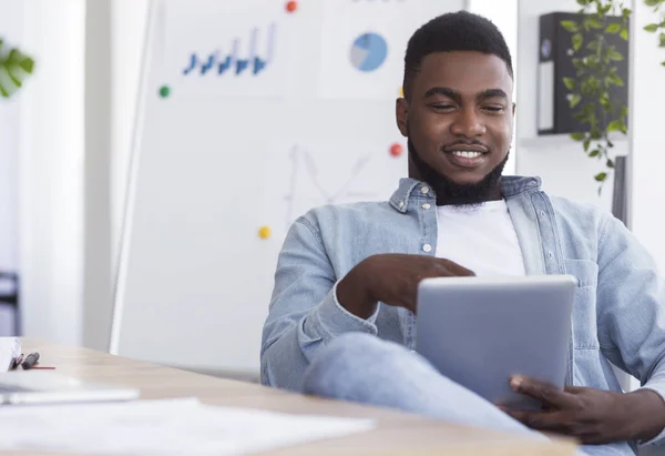 Relaxált afro-amerikai alkalmazott digitális füllel a munkahelyen — Stock Fotó