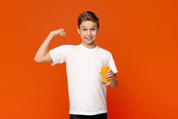Adolescente confiante com suco de laranja mostrando bíceps forte — Fotografia de Stock