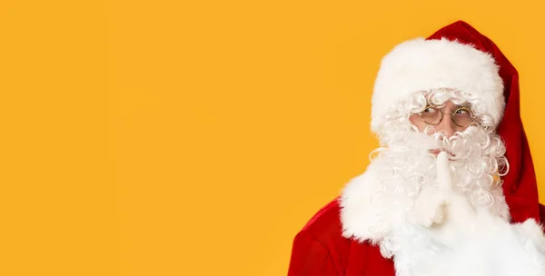 Santa Claus con el dedo cerca de la boca sobre fondo naranja — Foto de Stock