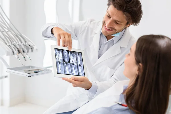 Bellissimo medico che mostra il risultato della radiografia del paziente su tablet digitale — Foto Stock