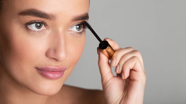 Beauty concept. Lady applying black mascara on eyelashes