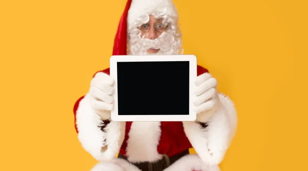 Santa Claus sorprendentemente mostrando una nueva tableta con pantalla en blanco — Foto de Stock