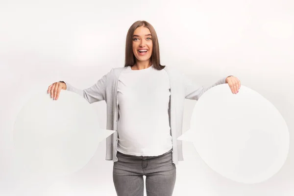 Zwangere vrouw houdt twee spraakbubbels staande, witte achtergrond, Mockup — Stockfoto