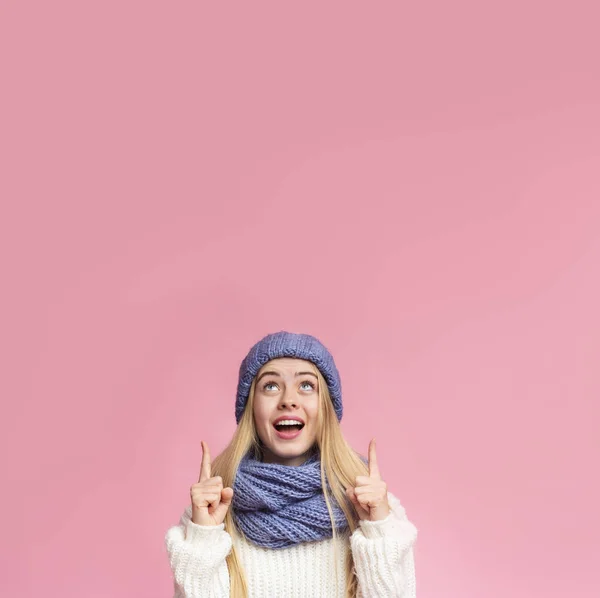 Amazed girl in blue hat pointing up at copy space — Stockfoto