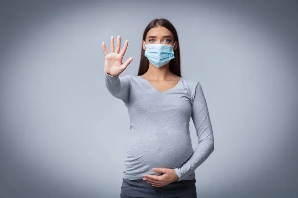 Zwangere dame in medische gezicht masker Gesturing Stop In Studio — Stockfoto