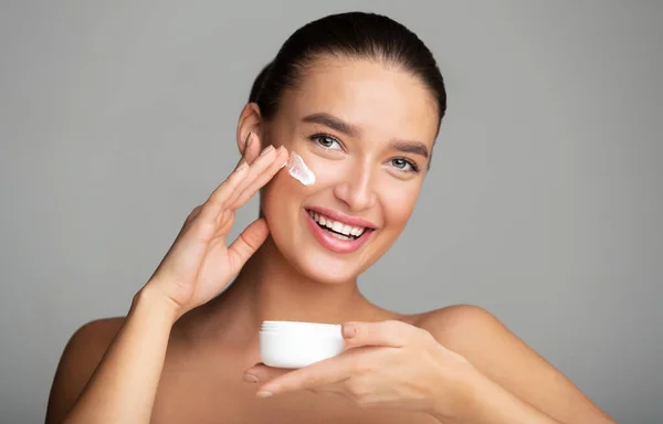 Cuidado de la piel e hidratante. Chica aplicando crema facial — Foto de Stock