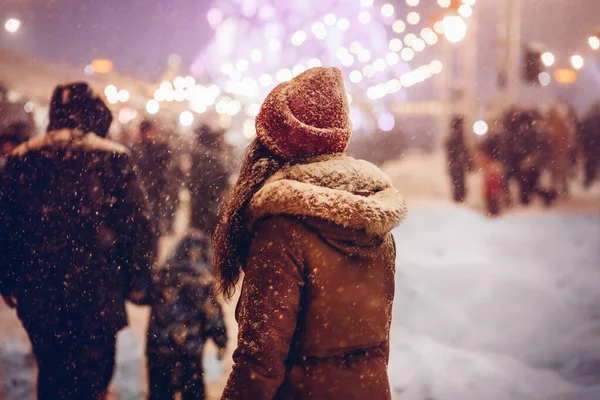 Chica caminando a través del mercado de Navidad en la ciudad por la noche —  Fotos de Stock