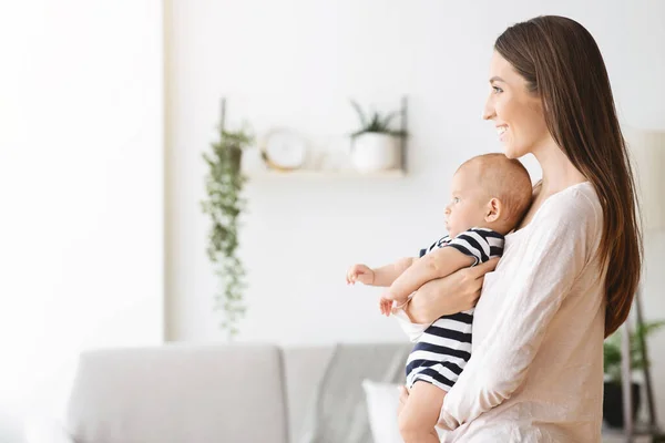 Güzel genç bir kadın kucağında sevimli bir bebek taşıyor. — Stok fotoğraf