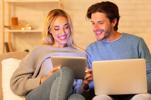 Веселые супруги с помощью ноутбука и цифрового планшета Websurfing дома — стоковое фото