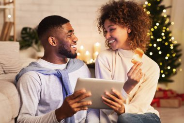 Noel için hazırlanıyorum. Heyecanlı Afrikalı çift internetten hediye alıyor.