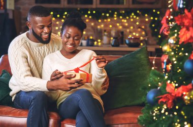 Mutlu Afrikalı Amerikalı kadın kocasının Noel hediyesini açıyor.