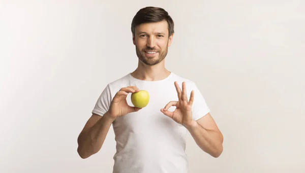 Homem segurando a Apple Gesturing OK em pé sobre fundo branco — Fotografia de Stock