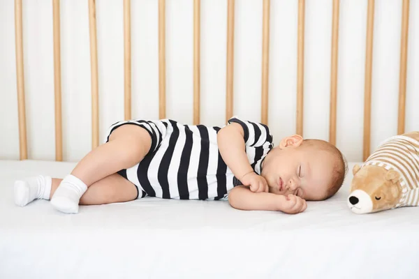 Precioso bebé recién nacido en traje de cuerpo siesta en cuna cómoda —  Fotos de Stock