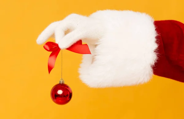 Papai Noel segurando pequena bola vermelha na mão em laranja — Fotografia de Stock