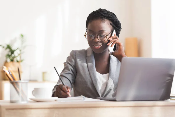 Afro Segretario Parlare al telefono e prendere appunti sul posto di lavoro — Foto Stock