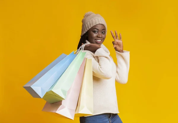 Zufriedenes schwarzes Mädchen mit Einkaufstüten, die Okay-Zeichen zeigen — Stockfoto