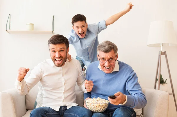 Emocionado anciano, hijo maduro y nieto viendo deportes en interiores — Foto de Stock