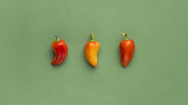 Açık yeşil arka planda üç parlak biber