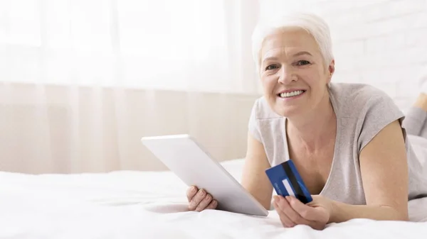 Femme âgée moderne faisant du shopping en ligne avec tablette numérique et carte de crédit — Photo