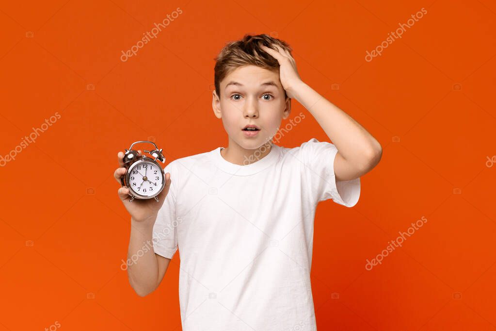 Worried awake teen boy with alarm clock