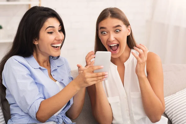 Gelukkig meisje tonen bericht naar vriend zitten op bank indoor — Stockfoto